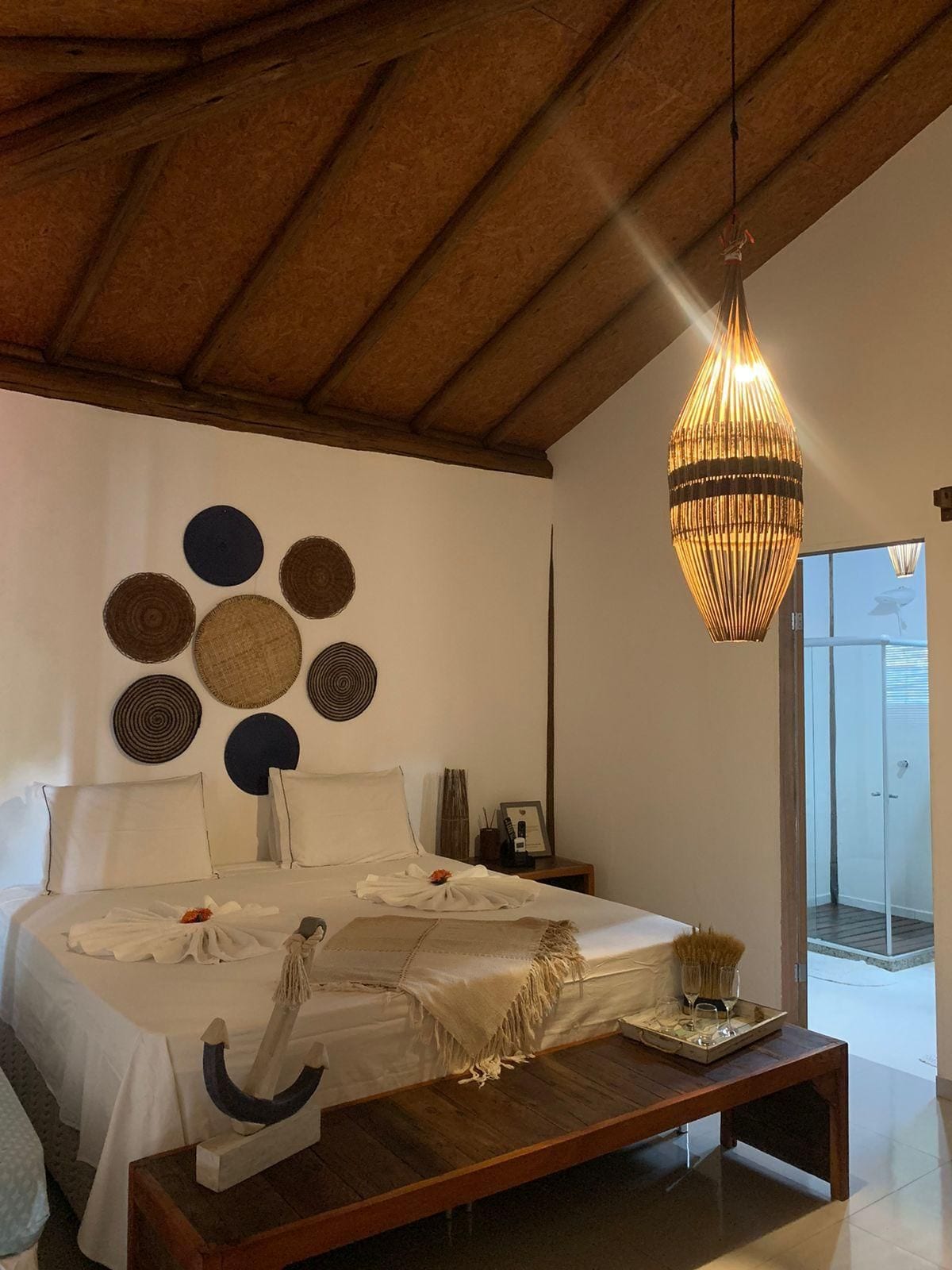 Un dormitorio con cama, mesitas de noche, una lámpara colgante y un cuadro circular en la pared.