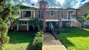Una casa de dos pisos con fachada de ladrillo, una estructura similar a una torre en el techo y un césped bien cuidado.