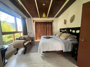 A bedroom with a bed, a chair, a table, and a window with curtains. - La Palapa by Otium (Alto Lucero)