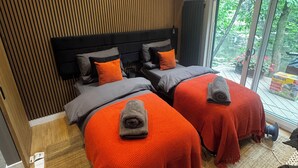 Een moderne slaapkamer met twee bedden, een dakraam en uitzicht op groen.