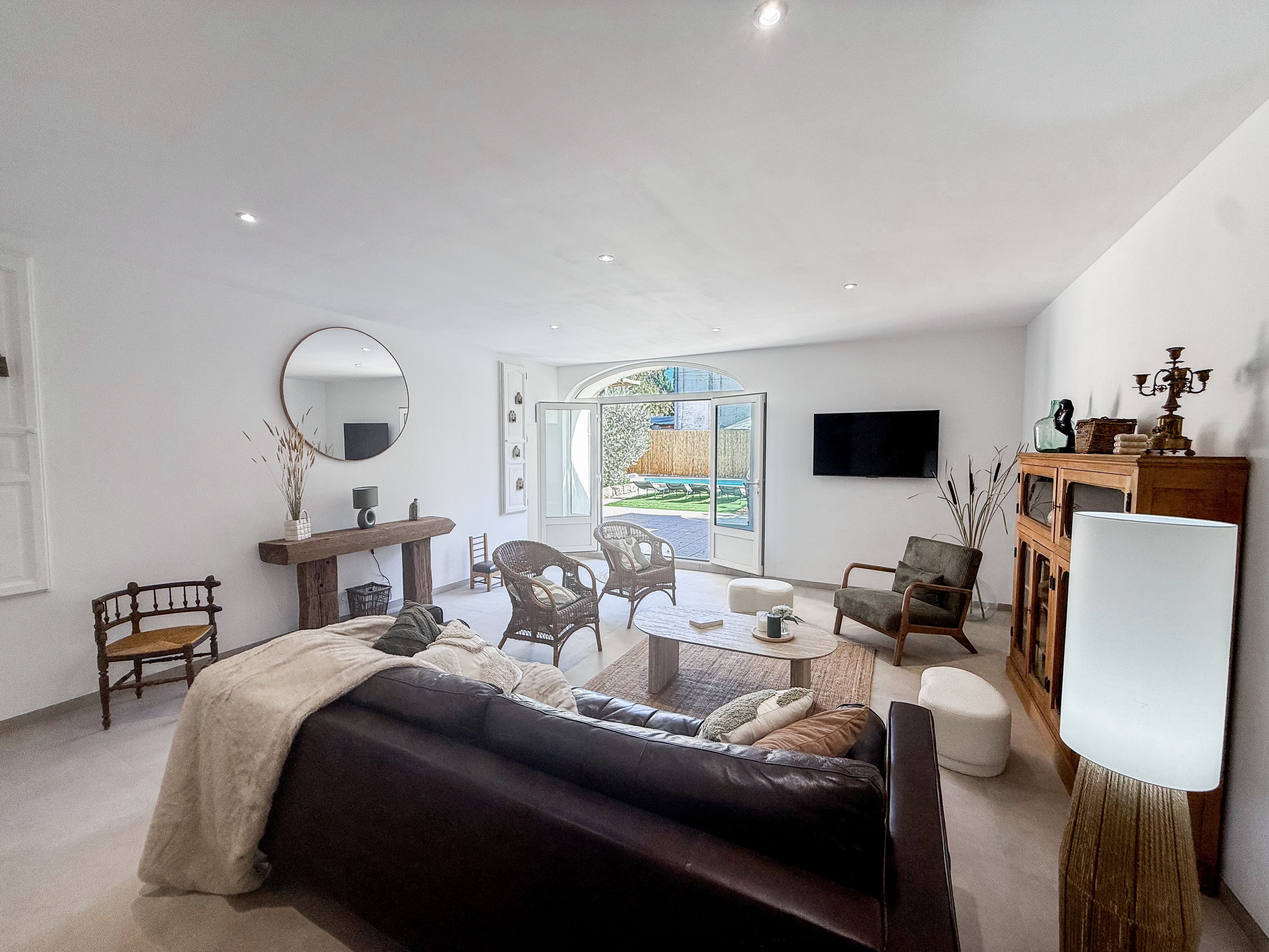 Een moderne woonkamer met een bank, fauteuils, een salontafel, een televisie en een groot raam.
