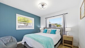 A bedroom with a bed, a bean bag chair, a nightstand, a window with curtains, and a ceiling light. - Family Oasis • Playset • Near Airport & Stadium (Tampa)