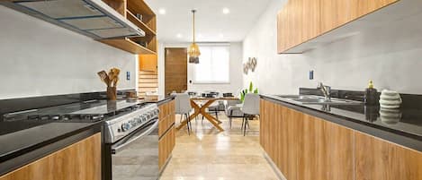 A modern kitchen with a central island, wooden cabinetry, and a dining area with a contemporary chair design.