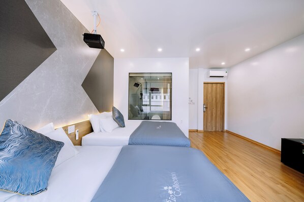 Habitación de hotel moderna con cama, mesita de noche y zona de ducha.