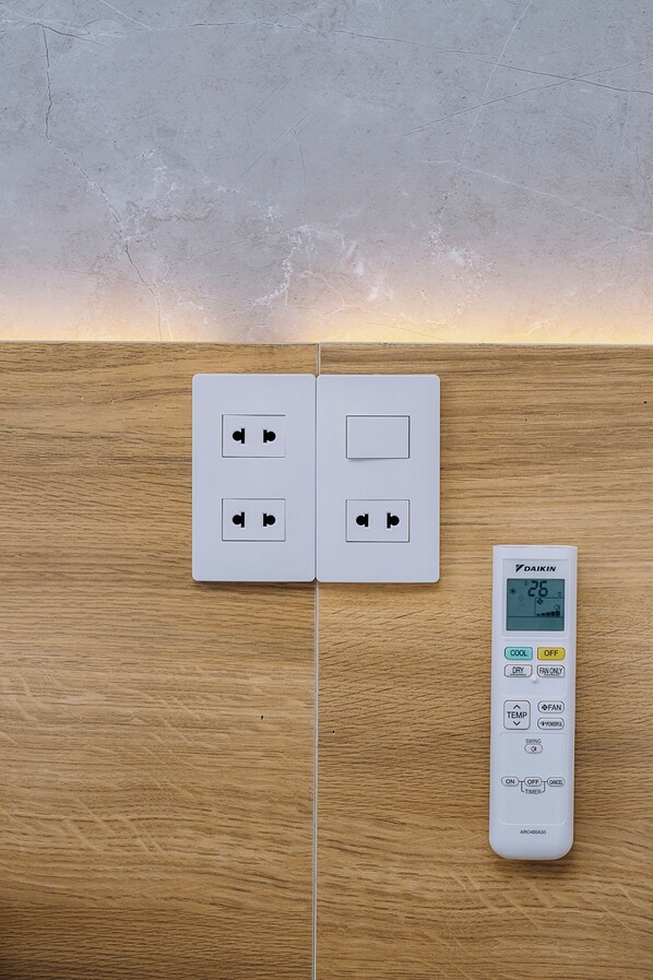 Toma corriente empotrada en la pared con dos enchufes y un termostato digital que muestra 26 grados.