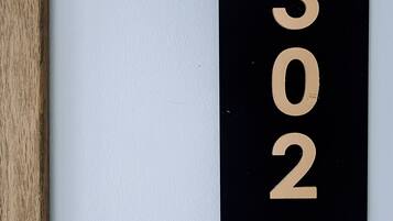 A black and gold room number sign with the numbers '302' mounted on a white wall.