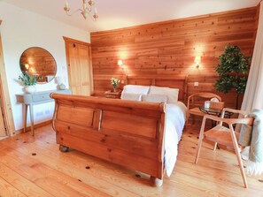 A wooden-paneled bedroom with a bed, bedside tables, a mirror, and a chair. - Deers Leap (Dalbeattie)