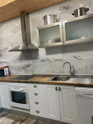 A modern kitchen with a stainless steel range hood, a double sink, and a built-in oven.