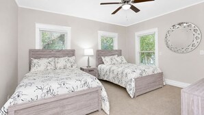 A bedroom with two beds, a ceiling fan, and a round mirror on the wall. - Fresh and Cozy Mansion Near Downtown (Kansas City)