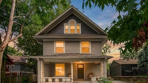 A two-story house with a front porch, a visible front door, and a small front yard. - Fresh and Cozy Mansion Near Downtown (Kansas City)