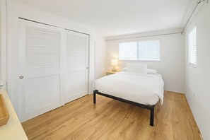 A bedroom with a bed, a nightstand, a lamp, and a window with blinds. - Bayview Jr. 2 Bedroom Bungalow (Nokomis)