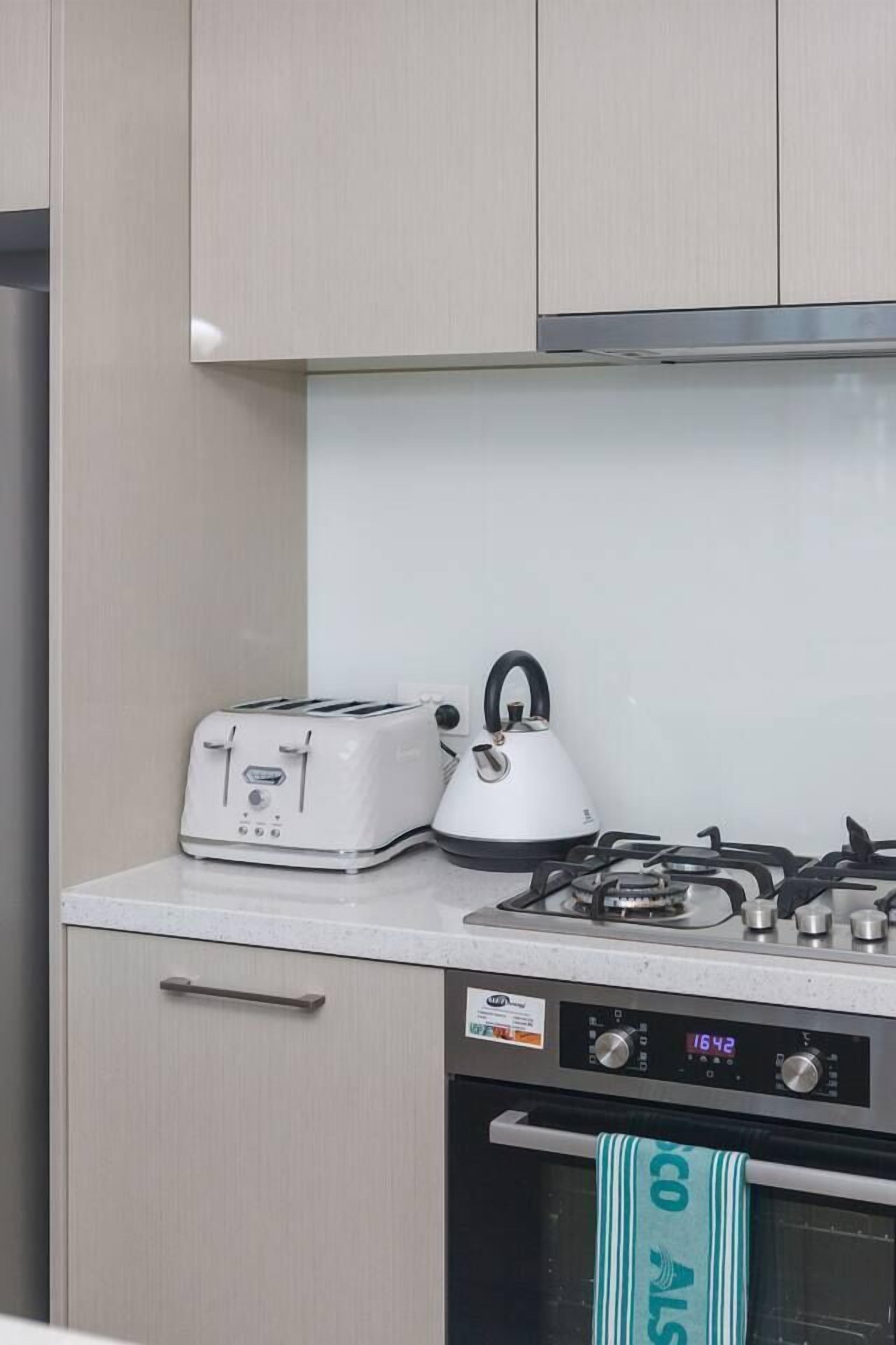 Een keuken met een broodrooster, waterkoker en gasfornuis.
