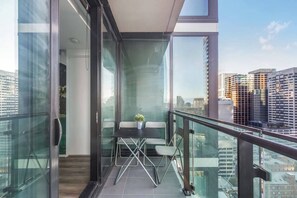 A modern balcony with a glass door, a small table with chairs, and a potted plant. - Starry Nights on Lonsdale Steps to Melbourne Icons (Melbourne)