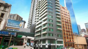 A high-rise building with multiple floors, a bus stop, and a clear blue sky. - Minimal at Altitude Poolside Stay by CBD Landmarks (Melbourne)