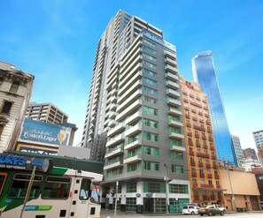 A high-rise building with multiple floors, a bus stop, and a clear blue sky. - Minimal at Altitude Poolside Stay by CBD Landmarks (Melbourne)