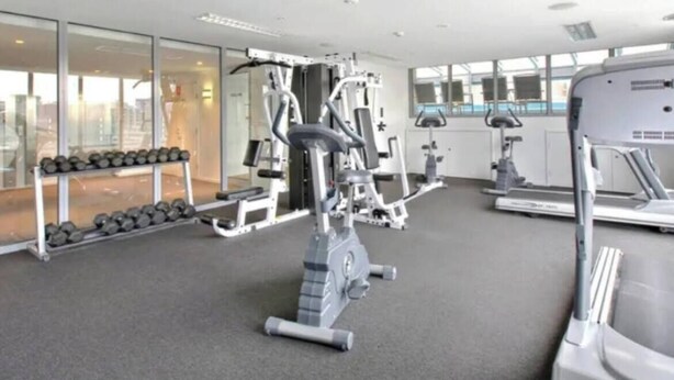 A gym with cardio machines, free weights, and a treadmill. - Minimal at Altitude Poolside Stay by CBD Landmarks (Melbourne)