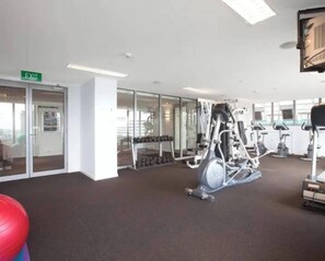 A gym with exercise equipment, a red exercise ball, and a door marked 'EXIT'. - Minimal at Altitude Poolside Stay by CBD Landmarks (Melbourne)