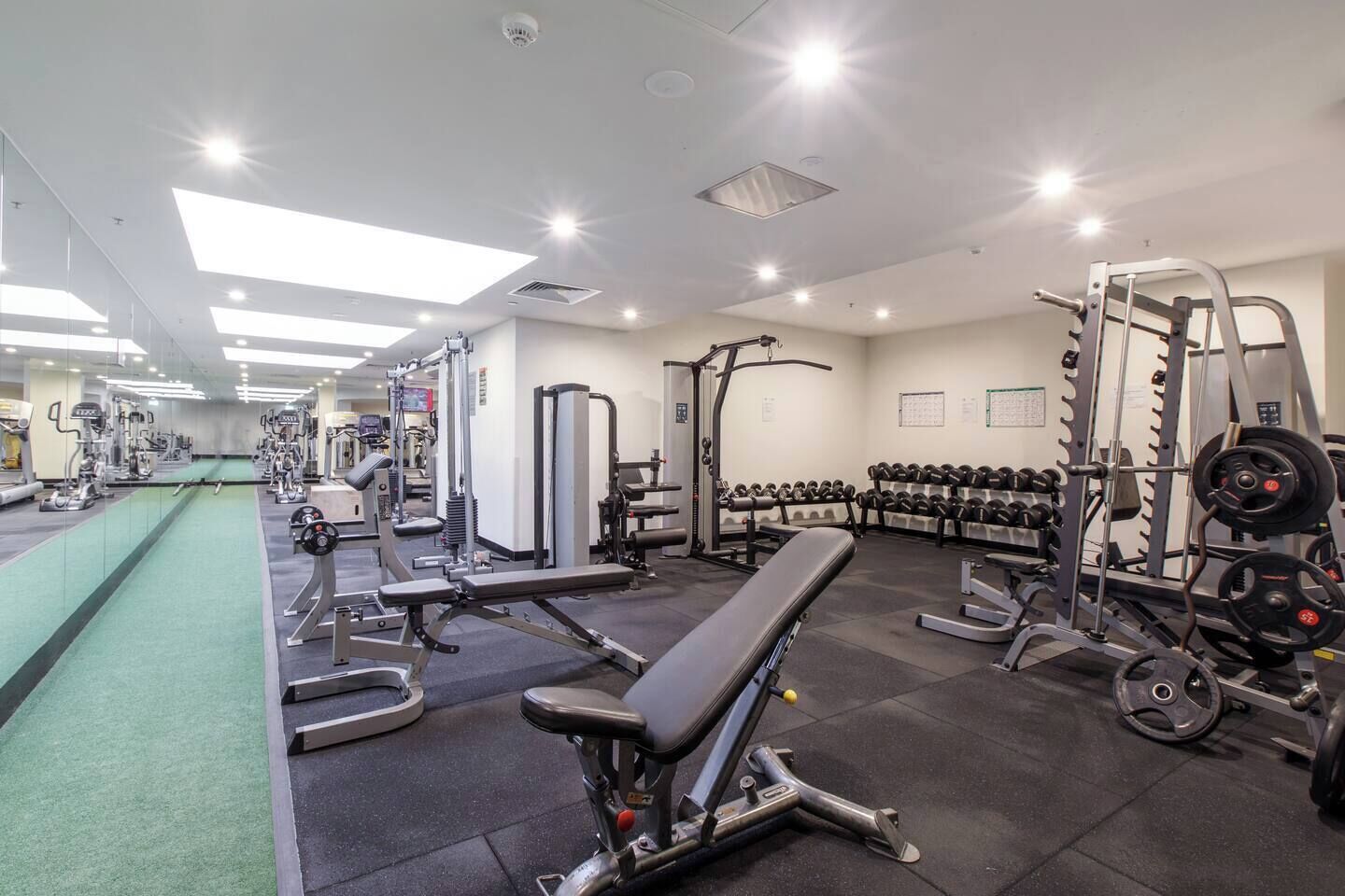 A gym with various exercise equipment, including benches, dumbbells, and weight machines.