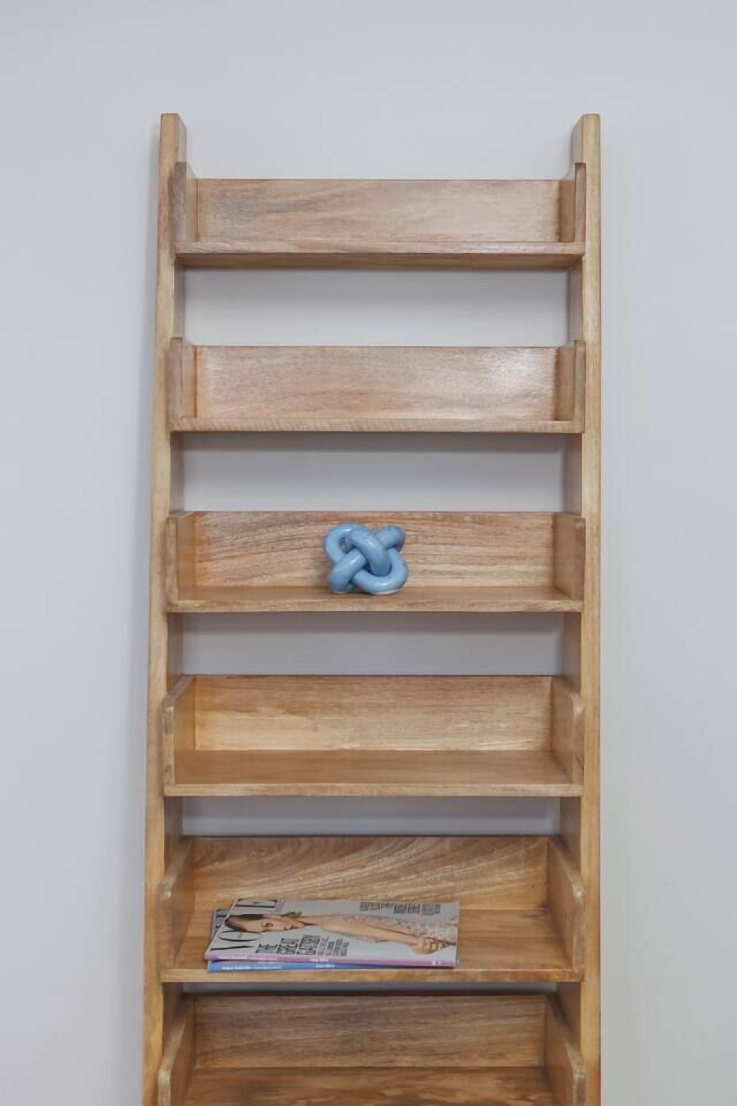 A wooden shelf unit with multiple compartments, one of which contains a magazine.