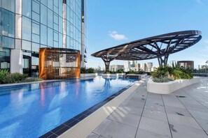 A modern building with a glass facade, a rooftop pool with a unique metal structure, and a city skyline in the background. - Southbank Sojourn Resort Comfort and Skyline Views (Southbank)