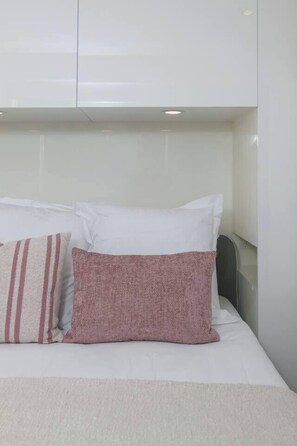 A bed with white and pink pillows, a white headboard, and a white wall. - Urban Calm Tranquil Retreat by Yarra River and Crown (Southbank)