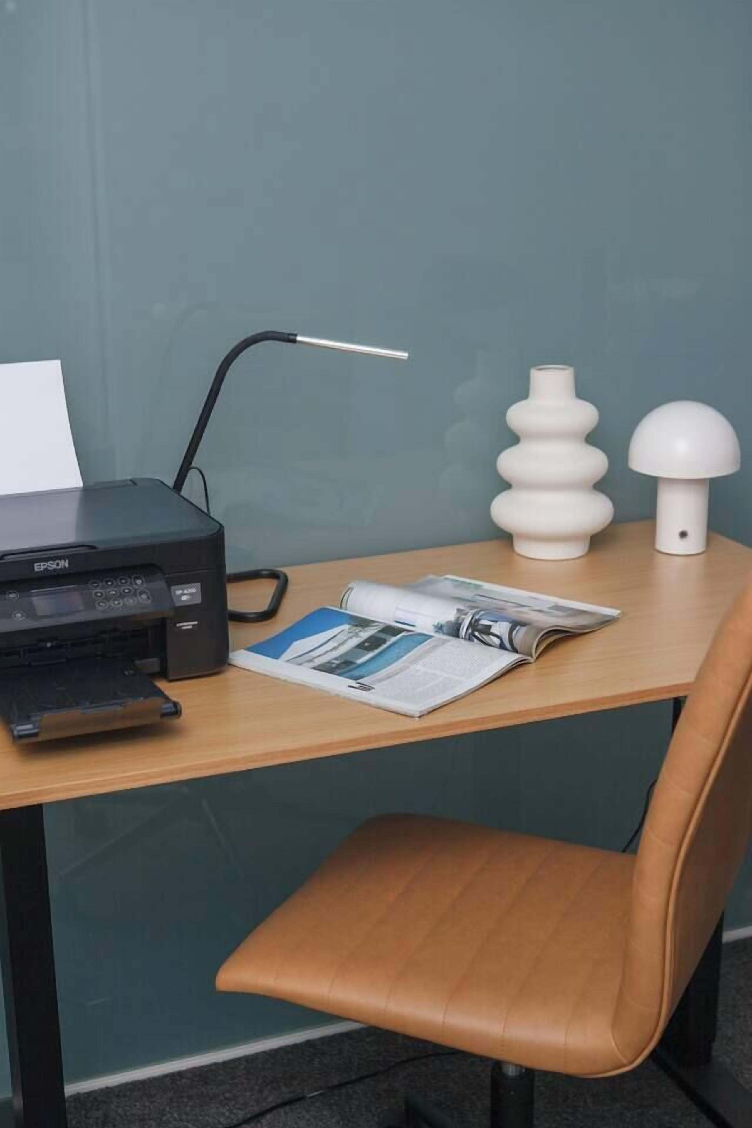 A desk with a printer, a lamp, and a chair.