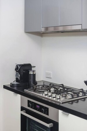A kitchen with a gas stove, a coffee maker, and a built-in oven. - Urban Calm Tranquil Retreat by Yarra River and Crown (Southbank)