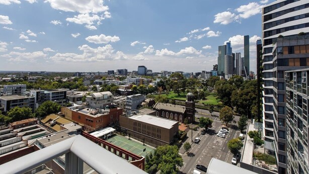 Paisagem urbana com edifícios modernos, quadra de basquete e céu limpo.