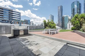 An outdoor urban space with a seating area, a trash bin, and a wall with graffiti. - Batman Hideout Modern Parkside Escape with Gym (West Melbourne)