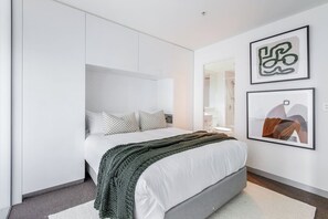 A modern bedroom with a bed, a wardrobe, and two framed artworks on the wall. - Batman Hideout Modern Parkside Escape with Gym (West Melbourne)