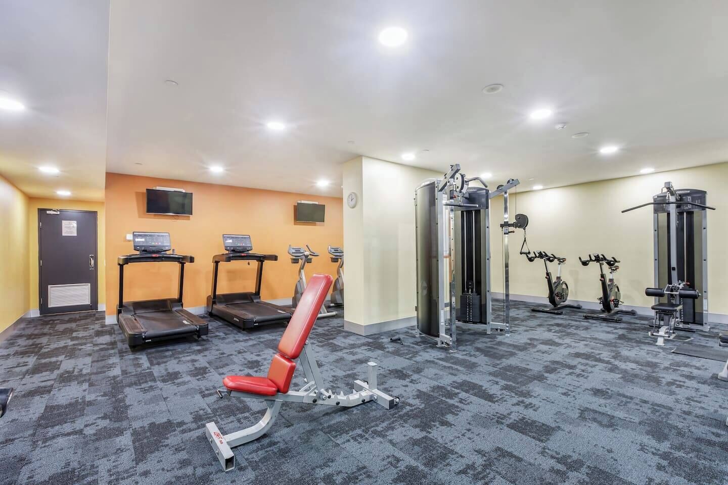 A gym with treadmills, a red bench, and various exercise machines.