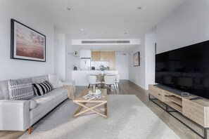 A modern living room with a sofa, coffee table, and TV stand. - Riverside Lustre Chic Resort Style Escape by Crown (Southbank)