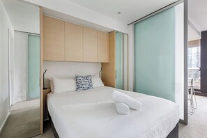 Ein modernes Hotelzimmer mit einem großen Bett, einem hölzernen Kopfteil und Blick auf die Stadt.