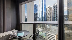 A balcony with a table and chairs, overlooking a cityscape with modern buildings. - Urban Cocoon Cosy Riverside Pad with Pool and Sauna (Southbank)