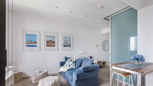 A modern bedroom with a blue sofa, a wooden desk, and a large mirror. - Urban Cocoon Cosy Riverside Pad with Pool and Sauna (Southbank)