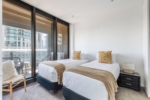 Ein modernes Hotelzimmer mit zwei Betten, einem Balkon und Blick auf die Stadtlandschaft.