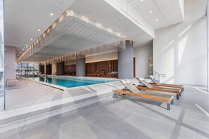 A modern indoor swimming pool with lounge chairs and a poolside area. - Yarra Vista Riverside City Escape by Crown Casino (Southbank)