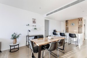 Eine moderne Küche mit einer zentralen Kochinsel, schwarzen Barhocker und einem Essbereich mit Holztisch und Stühlen.