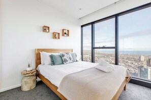 A modern hotel room with a large bed, a view of the city, and a small side table. - Oriana Refined Skyline Retreat by Yarra River (Southbank)