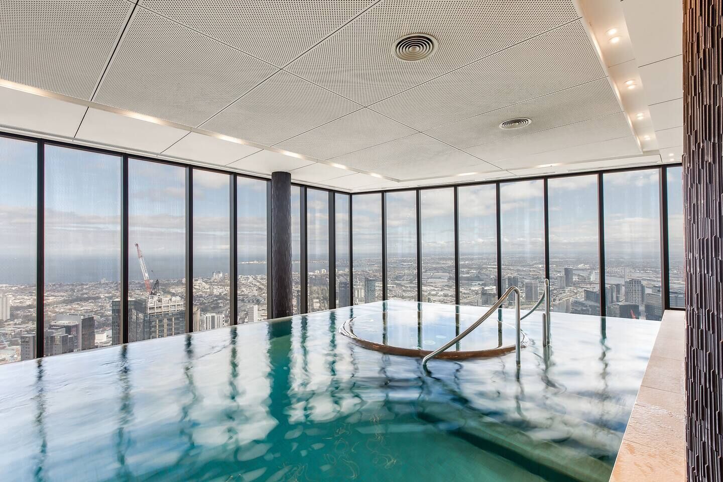 A high-rise building with a panoramic city view, a glass infinity pool, and a modern ceiling design.