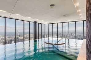 Ein Hochhaus mit Panoramablick auf die Stadt, einem gläsernen Infinity-Pool und einem modernen Deckenstil.