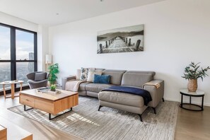 Een moderne woonkamer met een bank, salontafel en een schilderij aan de muur.