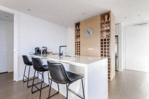 Eine moderne Küche mit einer zentralen Kochinsel, Barhocker, einer Uhr und eingebauten Regalen.