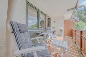 Ein Balkon mit zwei Loungestühlen, einem kleinen Tisch und einem Blumentopf.
