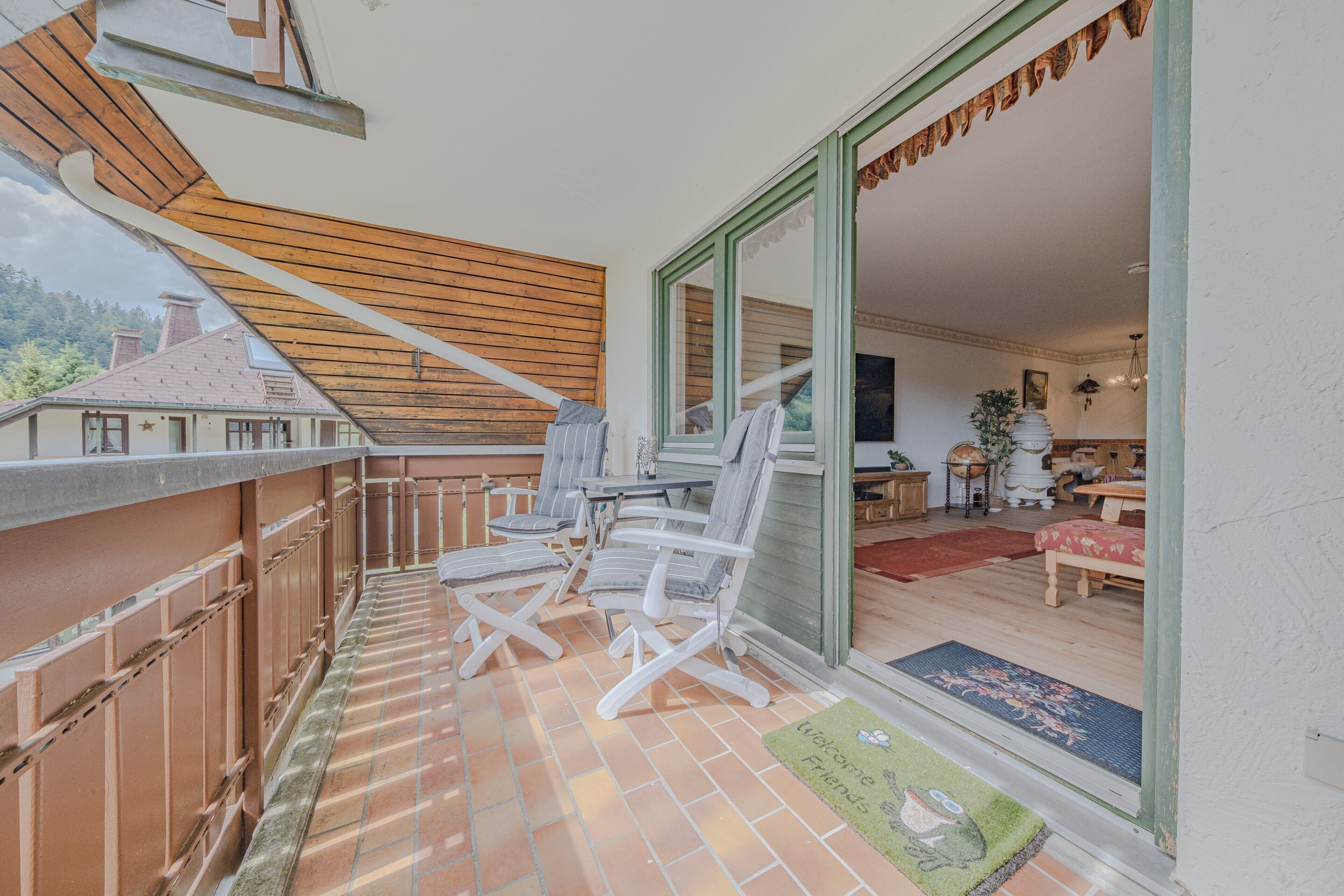 Ein Balkon mit Holister Holzschindeln, Blick ins Freie und eine Tür zu einem Innenraum mit Essbereich.