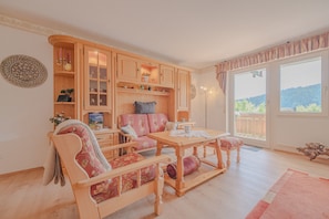 Ein gemütliches Wohnzimmer mit einem Holzdilettanten, einem Holzesstisch und Blick auf einen Balkon.