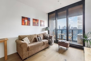 Un salon moderne avec une grande fenêtre, un canapé, une petite table et une plante en pot.