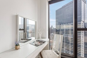 A modern room with a large window, a white bench, a glass table with magazines, and a decorative tree sculpture. - Evara Resort Style Living by Yarra River and Crown (Southbank)