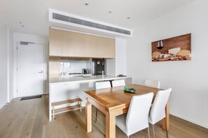 Une cuisine moderne avec des meubles blancs, une table à manger en bois et une seule chaise.