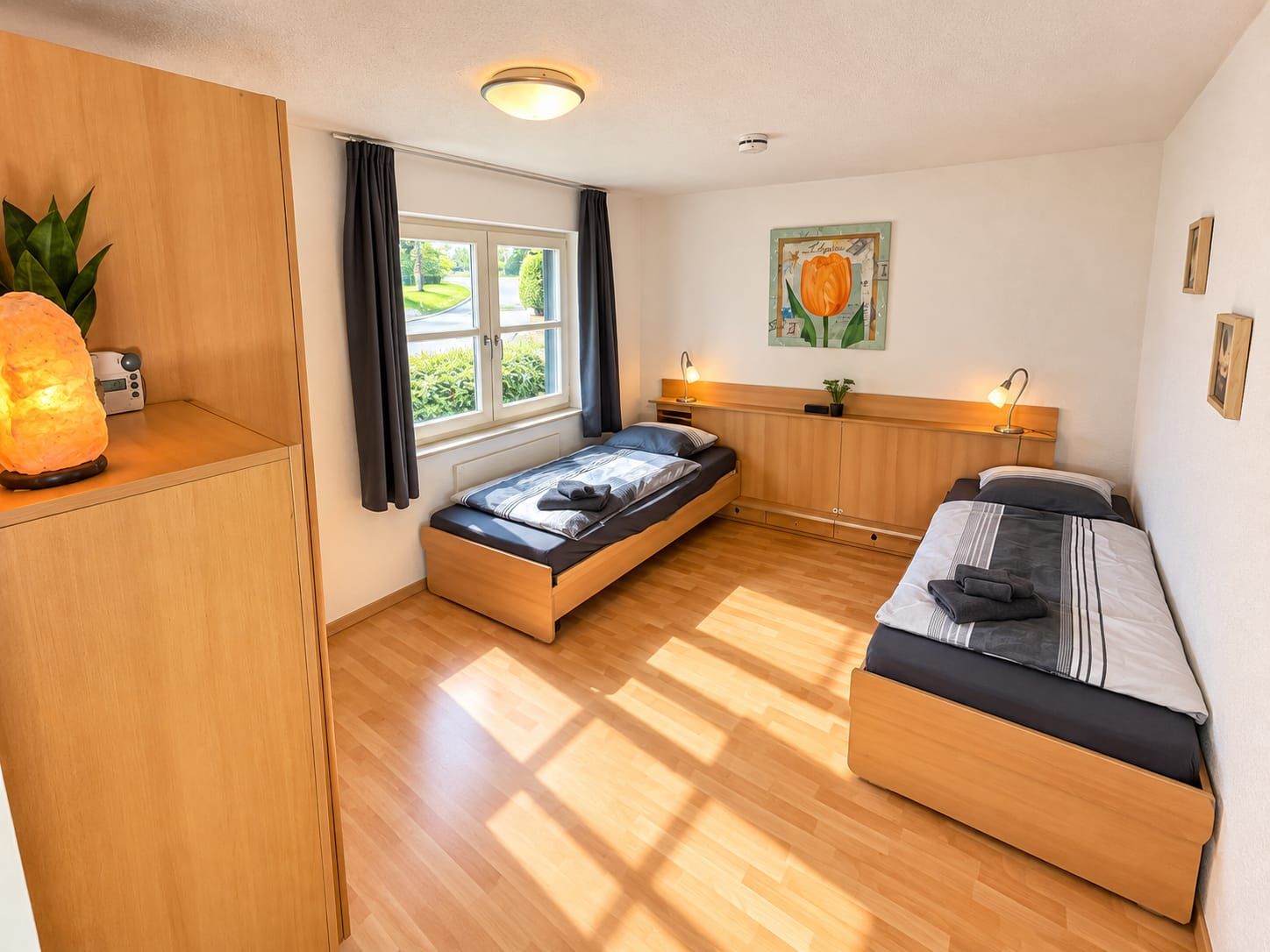Ein kleines Schlafzimmer mit Bett, Nachttisch und einem Fenster mit Vorhängen.